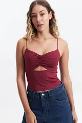 Top de breteles finos color bordó, con diseño ajustado al cuerpo, escote fruncido y abertura cut-out triangular en el centro del pecho.