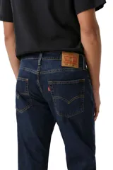 Pantalón de jean corte slim taper, con ajuste entallado en el muslo y pierna que se estrecha hacia el tobillo. Presenta un lavado azul oscuro clásico con costuras en contraste y cierre frontal con botón y cremallera.