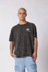 Remera negra con efecto acid wash, corte oversize y pequeño estampado tipográfico en el pecho con la frase 'A daily meeting point'.