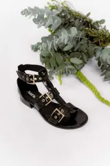 Sandalia de cuero vacuno color negro, con múltiples tiras y hebillas metálicas ajustables. Tiene taco bajo, forro y plantilla de cuero, y suela sintética.