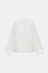 Camisa de cuello redondo confeccionada en mezcla de lyocell con acabado satinado. Presenta manga larga con puños, bolsillos de plastrón frontales y cierre mediante alamares.