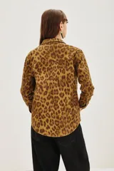 Campera de canvas con estampado animal print de leopardo, corte recto, cuello camisero, cierre frontal con botones metálicos y bolsillos frontales con solapa.