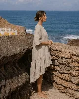 Vestido corto de lino color blanco, con mangas cortas amplias, escote redondo y diseño asimétrico más corto en la parte delantera y con volados en el ruedo.