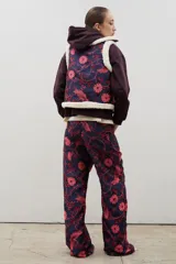 Pantalón de tiro alto y corte recto, confeccionado en tela brocato con estampado floral y de aves en tonos azul marino y rosado.