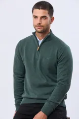 Buzo tejido de punto color verde oscuro, con cuello alto y cierre frontal parcial. Presenta un detalle en cuero en el tirador del cierre y un pequeño logo bordado en el pecho.