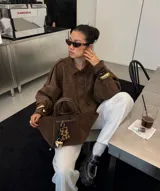 Chaqueta tipo bomber de color marrón, confeccionada en gamuza, con cuello camisero, mangas amplias y corte holgado a la cintura.