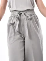 Pantalón de corte ancho y tiro alto, con cintura elástica y lazo ajustable del mismo tejido.
