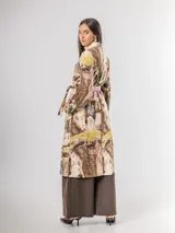 Trench de diseño urbano con acabado agamuzado, de corte recto y largo midi. Presenta un estampado abstracto multicolor con tonos rojizos, azules y ocres, cuello solapa, mangas largas y cinturón ajustable en la cintura.