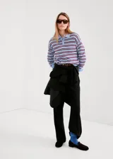 Jersey de punto celeste con rayas horizontales marrones y finas rayas blancas, cuello polo con solapa y cierre frontal de botones cortos, y mangas largas.