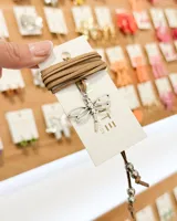 Choker de tiento de gamuza color tostado con dije central de libélula en metal plateado y terminaciones con cuentas metálicas.