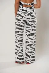Pantalón de tiro medio con corte recto y holgado, confeccionado en lino con estampado de peces en color negro sobre fondo blanco.