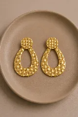 Aros colgantes de diseño geométrico con forma de gota, realizados en metal dorado con textura martillada.