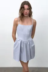 Vestido mini con estampado de cuadros vichy en color celeste y blanco, con escote redondo, tirantes finos ajustables, varillas interiores y falda con volumen.