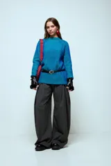 Sweater de punto con hilo de lurex brillante, color azul con rayas verticales en verde. Presenta cuello redondo, mangas largas con puños de piel sintética negra y corte holgado.