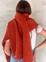 Chal de punto bouclé color marrón claro, hecho de 100% baby alpaca. Tejido suave, esponjoso y cálido, ofrece una textura envolvente y lujosa.