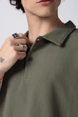 Chomba de manga corta con cuello polo, confeccionada en tejido de punto acanalado de textura pesada. Presenta un calce relajado y cuenta con una pequeña etiqueta distintiva en el ruedo.