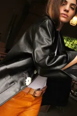 Blazer de cuero color celeste metalizado, con solapas, cierre con broches tipo tanca de madera y puños con detalle de piel sintética marrón.