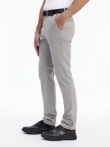 Pantalón chino de sarga elástica, color gris claro, de corte slim y talle medio. Incluye un cinturón negro con hebilla en forma de D.