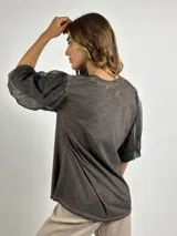 Blusa negra de manga 3/4 con cuerpo de algodón liso y mangas abullonadas de tejido transparente y arrugado.