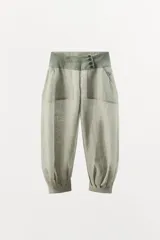 Pantalón bombacho de lino con tiro bajo, cintura ancha a contraste con cierre de botones, bolsillos laterales y bajo abullonado con puño.