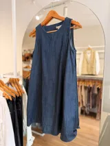 Vestido corto de denim azul sin mangas, con corte evasé amplio y fluido.