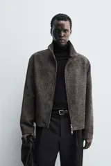 Sobrecamisa de corte relajado confeccionada en tejido con viscosa, de color gris oscuro con textura. Presenta cuello subido, cierre frontal con cremallera y bolsillos de vivo en la cadera.