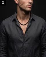 Collar de cuentas de piedra volcánica negra con detalles de eslabones cilíndricos de acero, diseño minimalista y masculino.