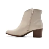 Botineta de cuero sintético color beige con detalle de hebilla dorada y taco de madera.