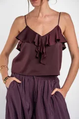 Musculosa negra de satén con escote en V, tirantes finos y detalle de volados en el pecho.
