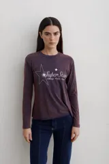Remera de manga larga con efecto lavado, cuello redondo y estampa frontal con diseño de estrella y texto.