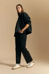 Jean de corte recto y tiro medio, confeccionado en denim elastizado de color negro. Presenta un diseño clásico con cierre de botón y cremallera, bolsillos laterales y traseros, y ruedo con terminación deshilachada.