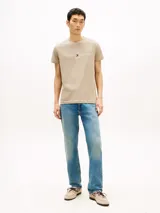 Remera Tommy Hilfiger de algodón color beige, de corte clásico con cuello redondo y manga corta. Presenta el logo de la marca bordado en el pecho junto con la inscripción "Est. 1985".