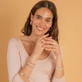 Anillo de diseño cruzado fabricado en plata 925 y oro, con una circonia central engastada y pequeños detalles de circonias laterales.