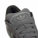 Championes Adidas Campus ST de color gris con franjas negras, diseño inspirado en la estética urbana de los años 90 y 2000, exterior de cuero con refuerzos de gamuza y suela de caucho resistente.
