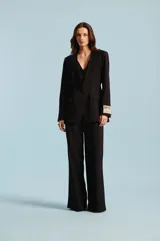 Saco sastre de mujer color negro, con apliques bordados de pedrería en los hombros, solapas cruzadas, cierre frontal de un botón y bolsillos con solapa.