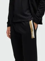 Pantalones deportivos negros de corte ajustado con una franja dorada en el lateral.