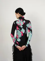 Polera de cuello alto y mangas largas, confeccionada en tela sublimada con estampado abstracto en tonos negro, verde, azul y rosa.