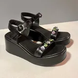 Sandalias de plataforma blanca con taco chino, tira en el empeine decorada con piedras acrílicas translúcidas y tira ajustable al tobillo con hebilla dorada.