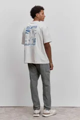 Remera de algodón color gris oscuro, de corte holgado y manga corta, con un pequeño estampado gráfico en el pecho.