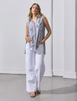 Camisa sin mangas de corte recto, con cuello clásico y escote en V. Presenta un diseño de rayas verticales en tonos lila, rosa, blanco y gris, con dos bolsillos frontales aplicados con estampado en chevron. Cuenta con cierre central de botones.