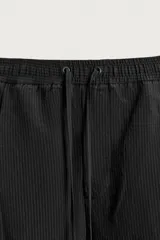 Bermuda relaxed fit de color negro, confeccionada en tejido fluido con viscosa y modal. Presenta cintura elástica ajustable con cordón, pliegues en el delantero, bolsillos frontales y bolsillos traseros de vivo.