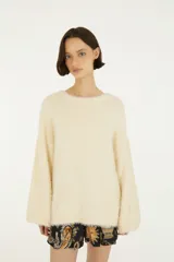 Sweater de tejido de punto con acabado afelpado, cuello redondo y mangas largas de volumen amplio. Diseño liso en color beige con silueta relajada.