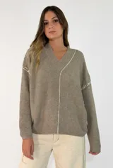 Sweater de punto color beige, con cuello en V, manga larga y costuras decorativas visibles en color blanco que recorren el centro y los hombros.