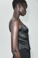 Top de satén negro estilo corsetero, con escote corazón, tirantes finos ajustables y cierre frontal con ganchos metálicos.