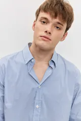 Camisa celeste de manga larga con cierre frontal de botones y cuello clásico.
