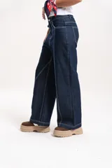 Pantalón de jean azul oscuro de corte recto y tiro medio-alto, con costuras a la vista en color blanco que resaltan el diseño.