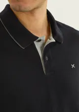 Chomba negra de manga corta con cuello camisero, cartera de botones y detalle bordado en el pecho.