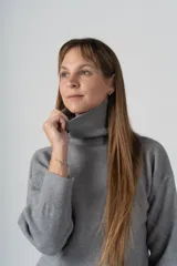 Sweater gris de tejido de punto, con cuello alto y mangas largas.