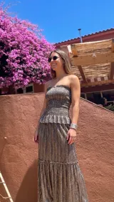 Vestido largo strapless de lamé elastizado metalizado, con cuerpo fruncido tipo nido de abeja, detalle de volado en la cintura y falda larga con frunces.