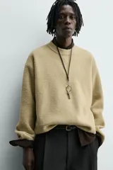 Jersey de punto con textura efecto pelo, corte relajado, cuello redondo y manga larga con acabados en rib.